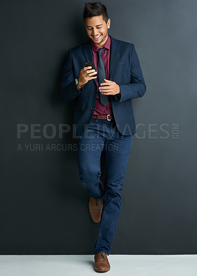 Buy stock photo Shot of a handsome young businessman texting on a cellphone against a black background