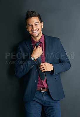 Buy stock photo Portrait of a handsome young businessman standing against a black background