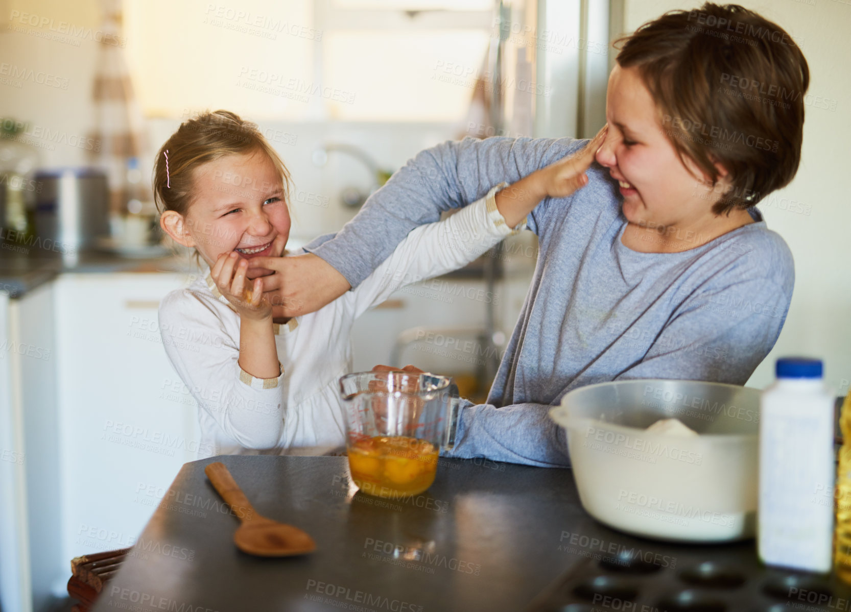 Buy stock photo Cropped shot of two young siblings having fun while baking together at home