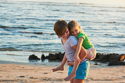 Buy stock photo Cropped shot of two young siblings enjoying the day together at the beach