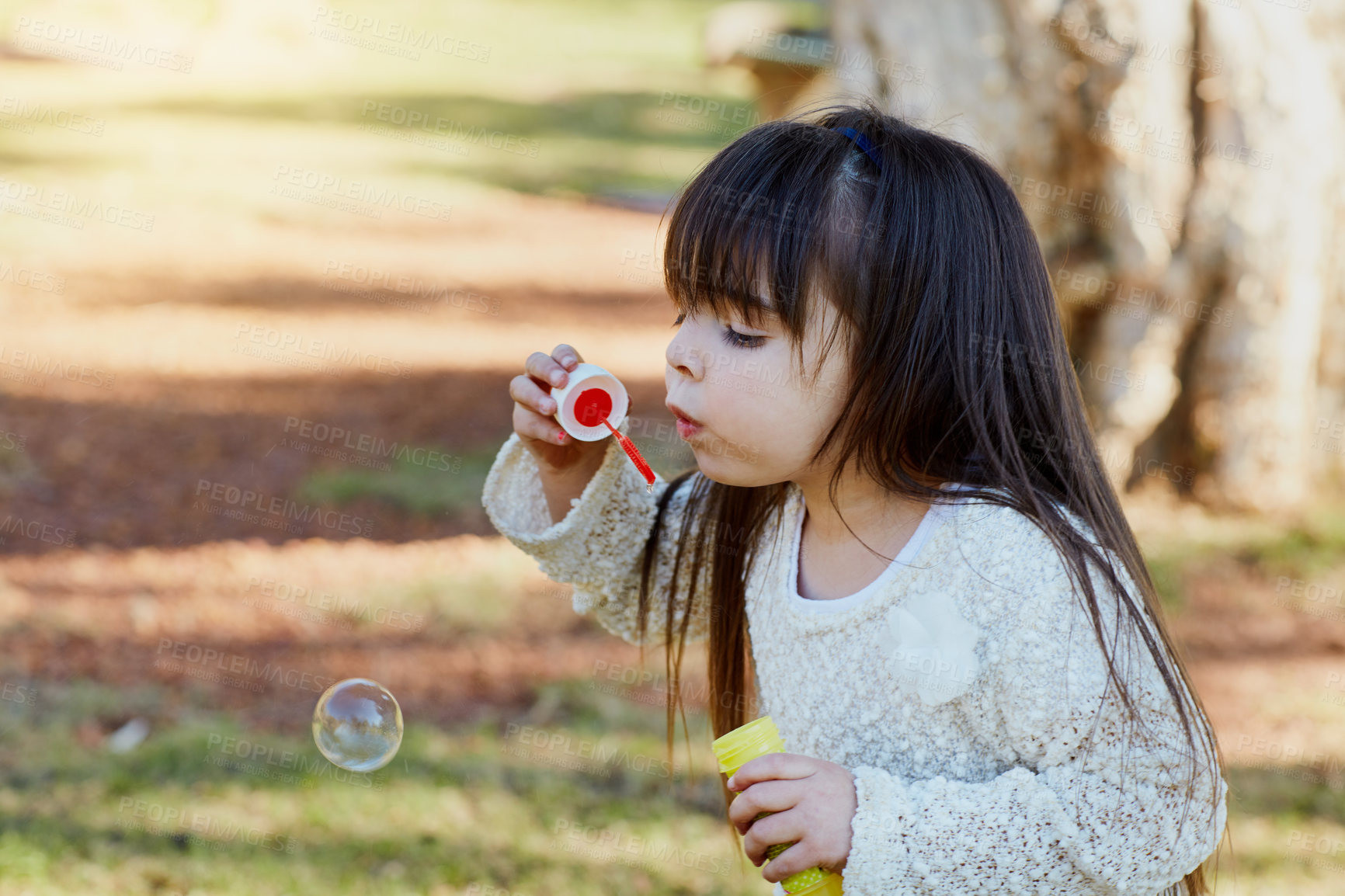 Buy stock photo Nature, outdoor and girl blowing bubbles, freedom and playing for fun, development and happiness. Female child, kid and young person in the park, soap and game with bubble wand, growth and vacation