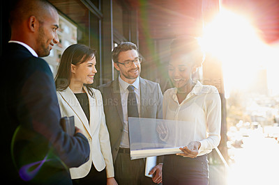 Buy stock photo Shot of a diverse group of businesspeople having a meeting on a balcony in bright sunlight