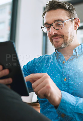 Buy stock photo Shot of a businessman using his tablet in the office
