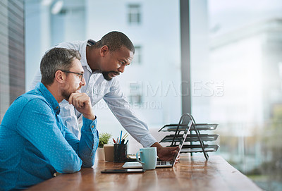 Buy stock photo Shot of two businessmen working on a laptop in their office