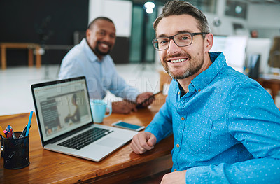 Buy stock photo Portrait of a businessman using his laptop with a colleague in the background