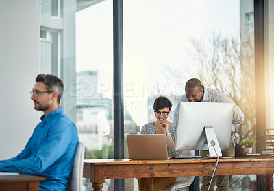 Buy stock photo Shot of a businessman working in the office with two colleagues in the background