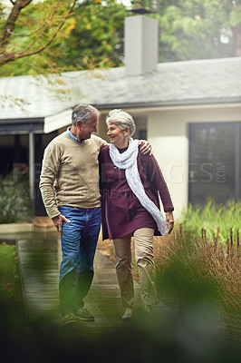 Buy stock photo Conversation, love and elderly couple walking in their garden by the house for wellness and fresh air. Bonding, retirement and senior man and woman on path together in their backyard at modern home.