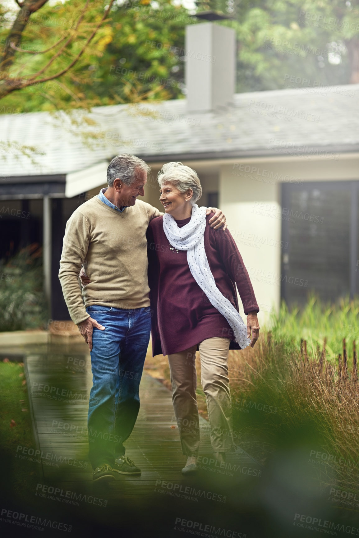 Buy stock photo Conversation, love and elderly couple walking in their garden by the house for wellness and fresh air. Bonding, retirement and senior man and woman on path together in their backyard at modern home.