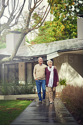 Buy stock photo Love, outdoor and elderly couple walking by their house for wellness, fresh air and bonding. Happy, retirement and senior man and woman on a path together in their garden at their modern home.