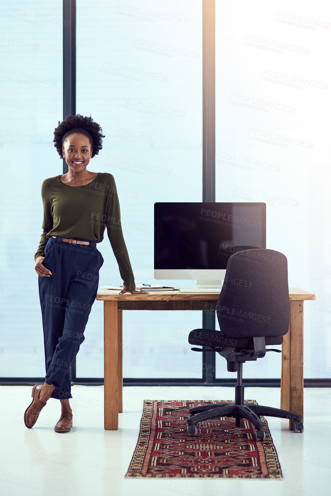Buy stock photo Portrait of a young designer leaning on her work station desk in front of a window