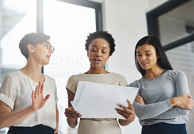 Buy stock photo Shot of a group of businesswomen analyzing paperwork together