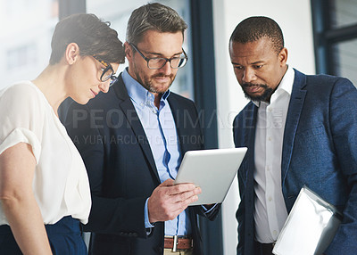 Buy stock photo Shot of a team of colleagues using a digital tablet together at work