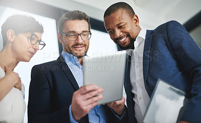 Buy stock photo Shot of a team of colleagues using a digital tablet together at work