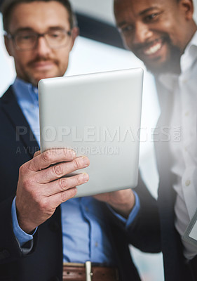 Buy stock photo Shot of two businessmen using a digital tablet together at work