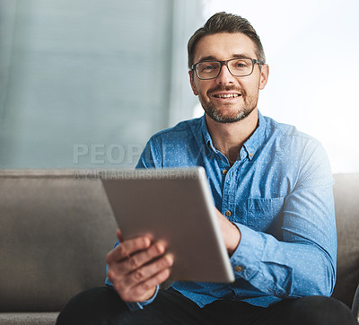Buy stock photo Portrait of a businessman using his digital tablet while sitting on a sofa in the office