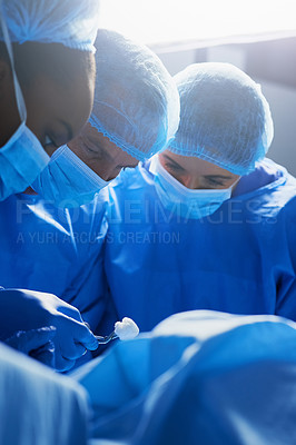 Buy stock photo Shot of group of surgeons working on a patient in an operating room