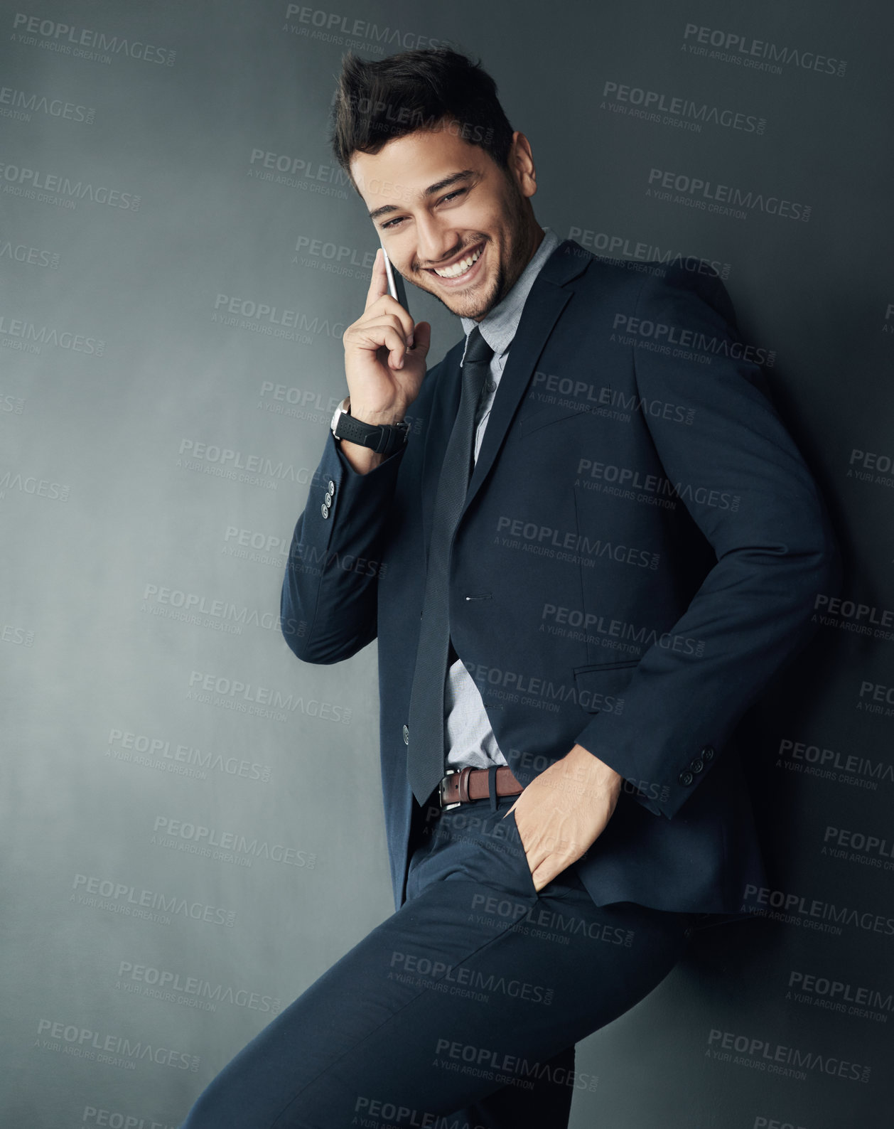 Buy stock photo Studio shot of a young businessman talking on a cellphone against a gray background