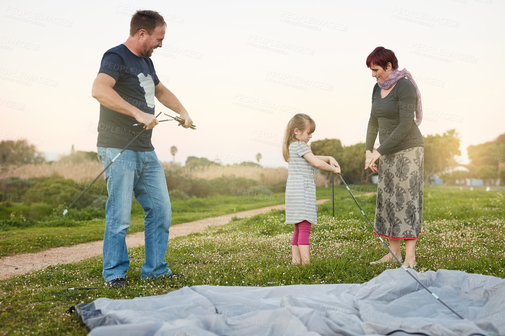 Buy stock photo Cropped shot of a young family putting up a tent together