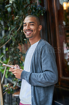 Buy stock photo Portrait of a young man texting on his cellphone outside