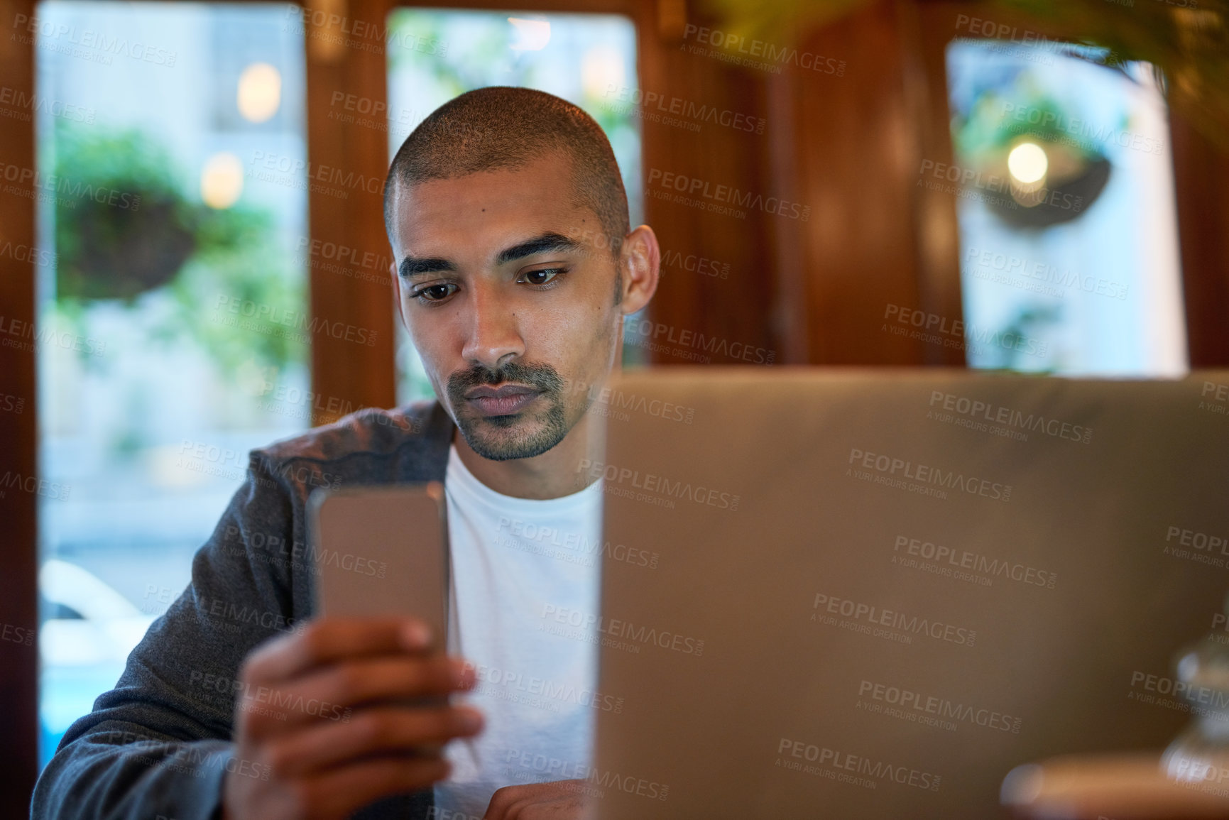 Buy stock photo Cropped shot of a young man texting on his cellphone in a coffee shop
