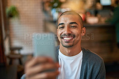 Buy stock photo Cropped shot of a young man texting on his cellphone in a cafe