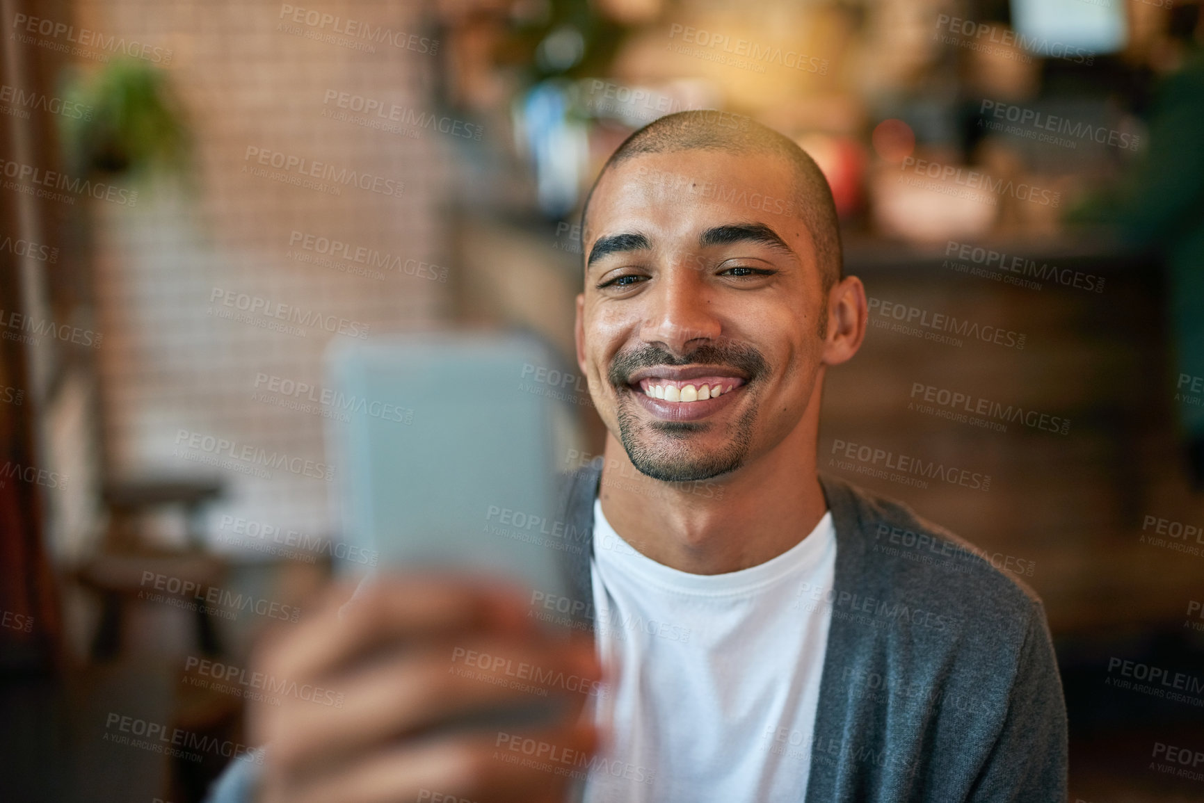 Buy stock photo Cropped shot of a young man texting on his cellphone in a cafe