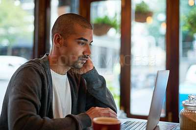 Buy stock photo Cropped shot of a young man working on his laptop in a cafe