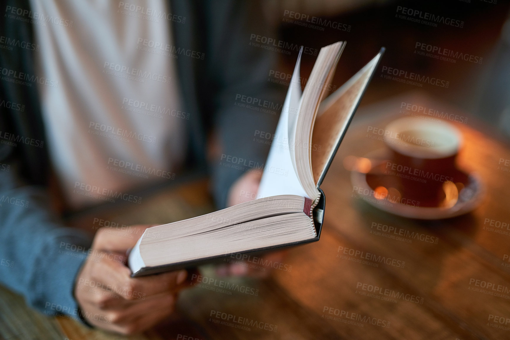 Buy stock photo Closeup shot of a young man reading a book in a cafe