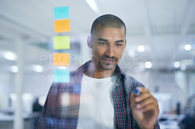 Buy stock photo Cropped shot of a young designer working on a glass wall in the office