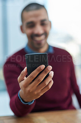 Buy stock photo Shot of a young businessman looking at his smartphone in the office