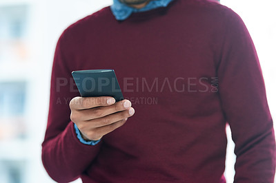 Buy stock photo Shot of an unidentifiable businessman using his smartphone in the office