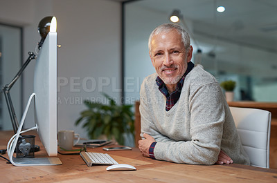 Buy stock photo Portrait of a smiling mature businessman working on a computer in an office