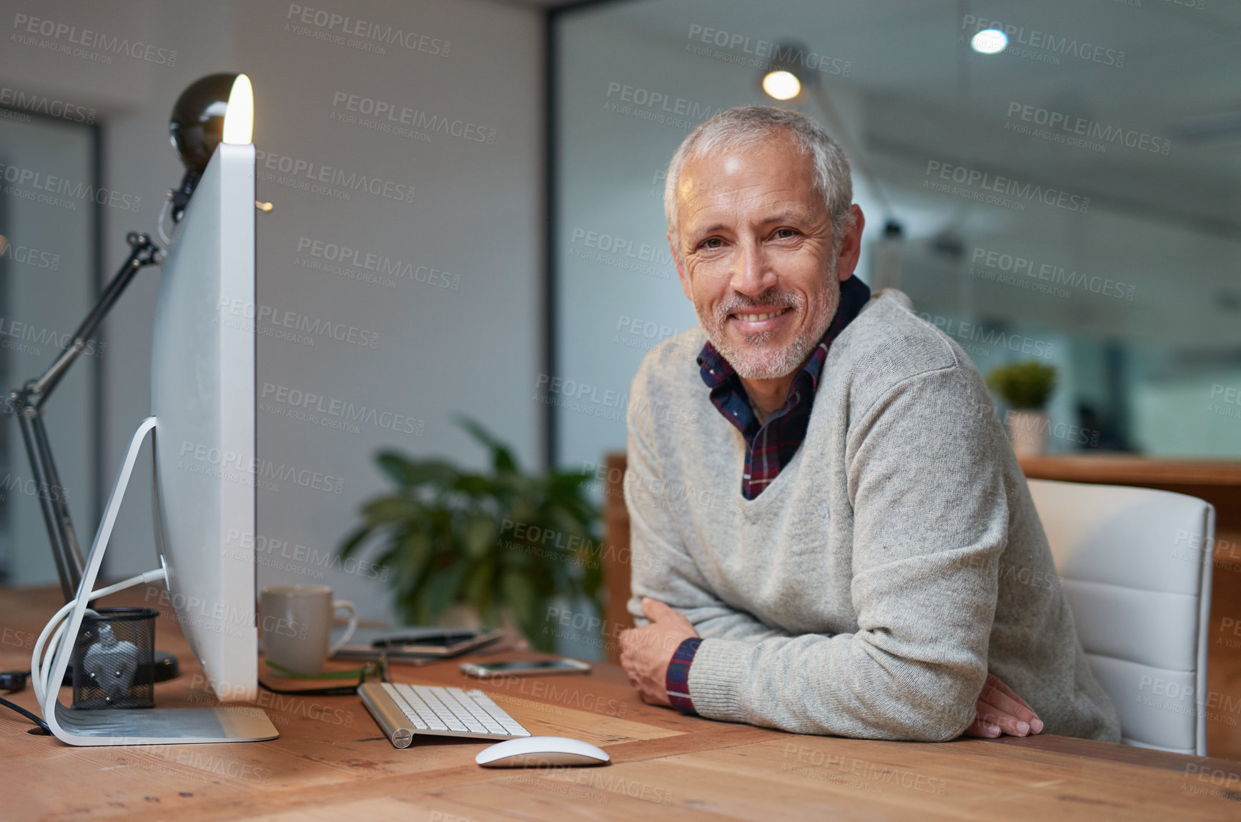 Buy stock photo Portrait of a smiling mature businessman working on a computer in an office