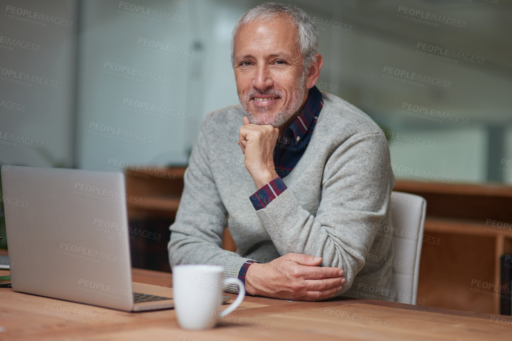 Buy stock photo Portrait of a smiling mature businessman using a laptop while working in an office