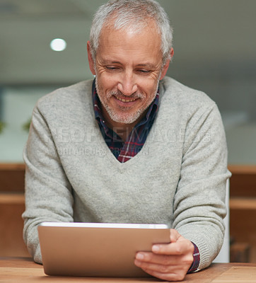 Buy stock photo Shot of a mature businessman using a digital tablet while working in an office