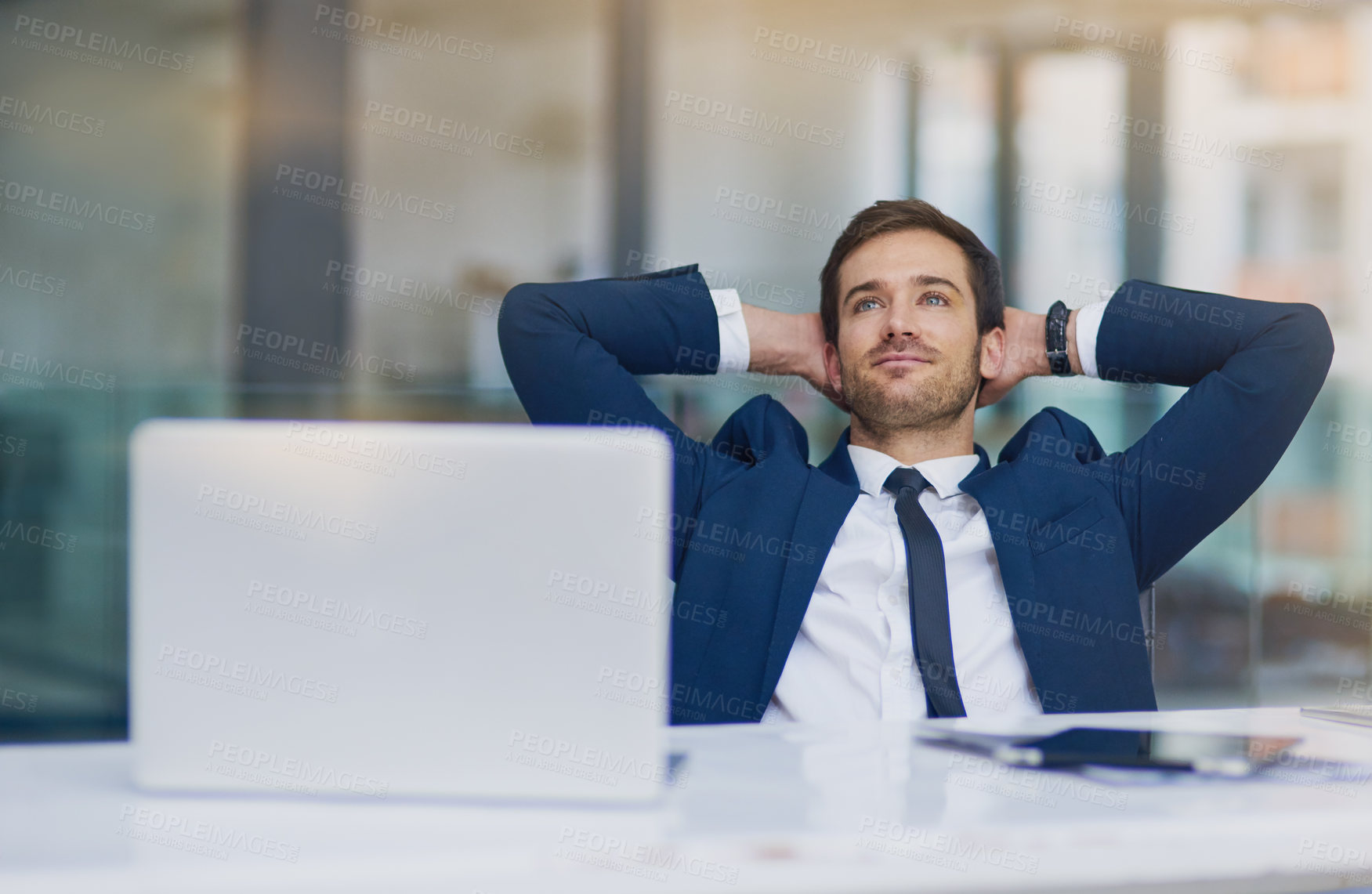 Buy stock photo Shot of a young businessman looking relaxed with his hands behind his head