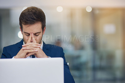 Buy stock photo Shot of a young businessman looking stressed while working in his office