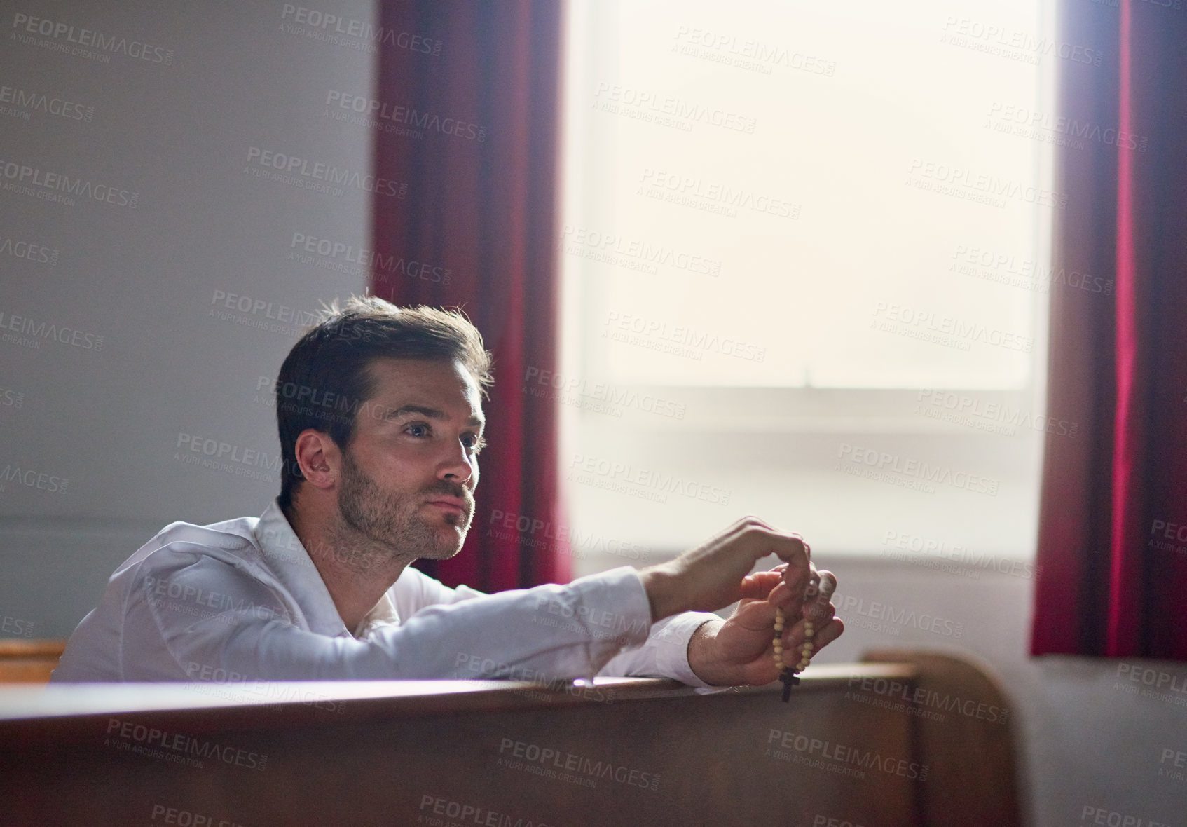 Buy stock photo Shot of a thoughtful young man sitting in a church