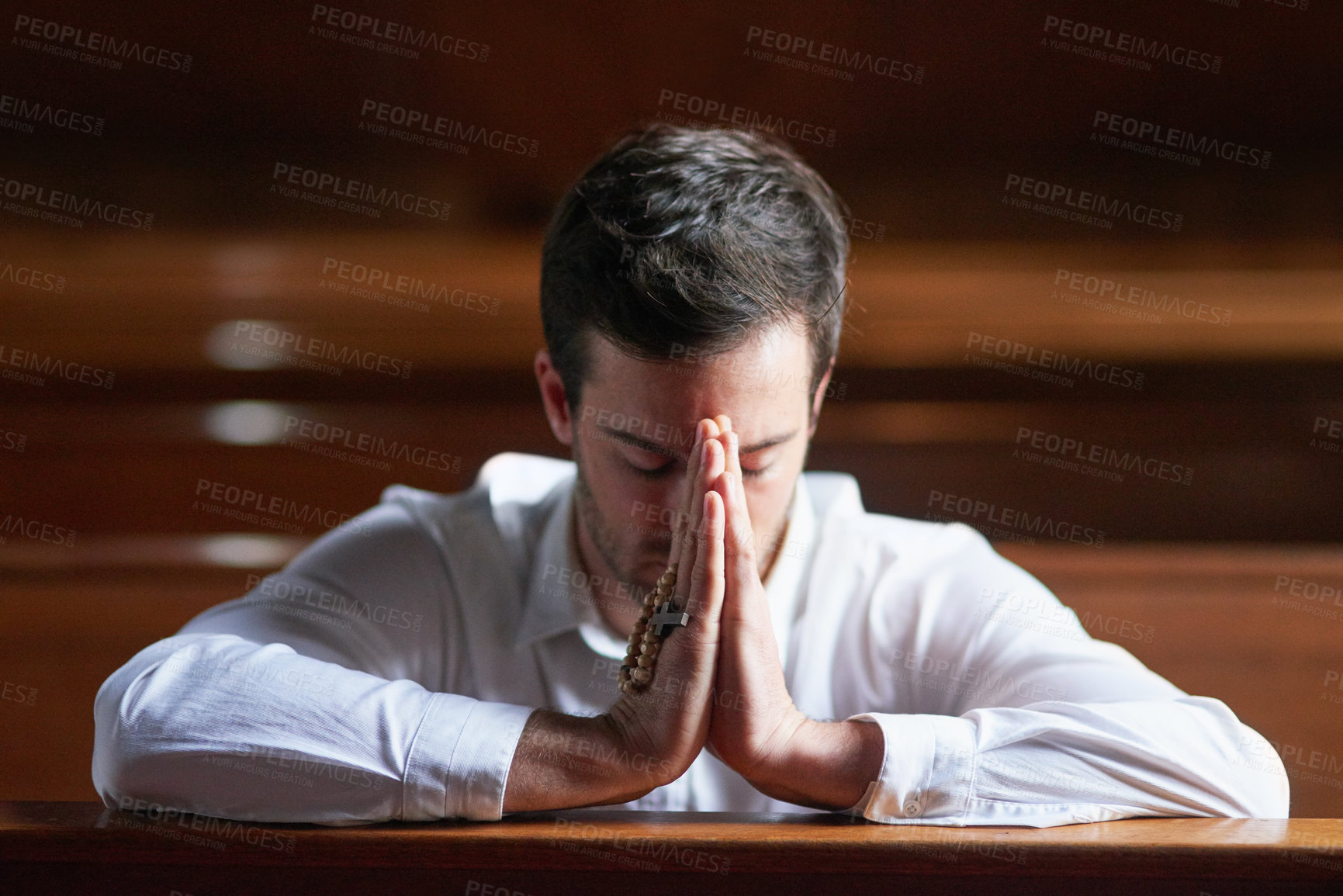 Buy stock photo Shot of a young man praying in a church