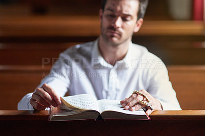 Buy stock photo Shot of a young man reading the bible in church