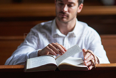 Buy stock photo Shot of a young man reading the bible in church