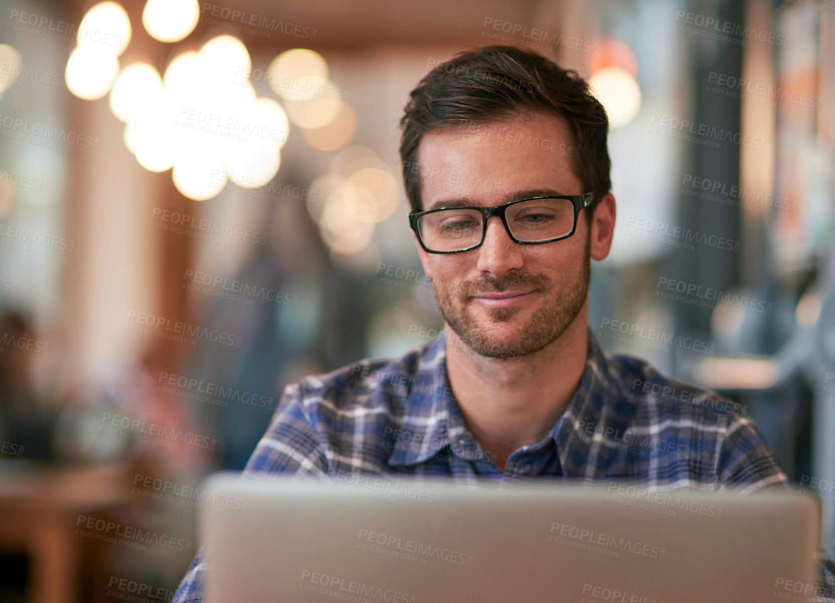 Buy stock photo Shot of a young man using his laptop while sitting in a coffee shop