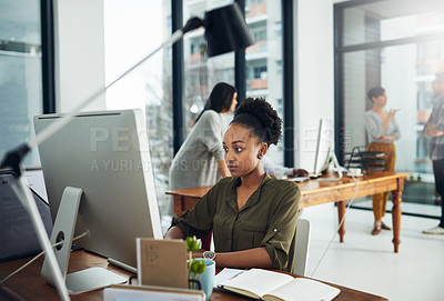 Buy stock photo Cropped shot of a young businesswoman working on a computer in a modern office with colleagues in the background