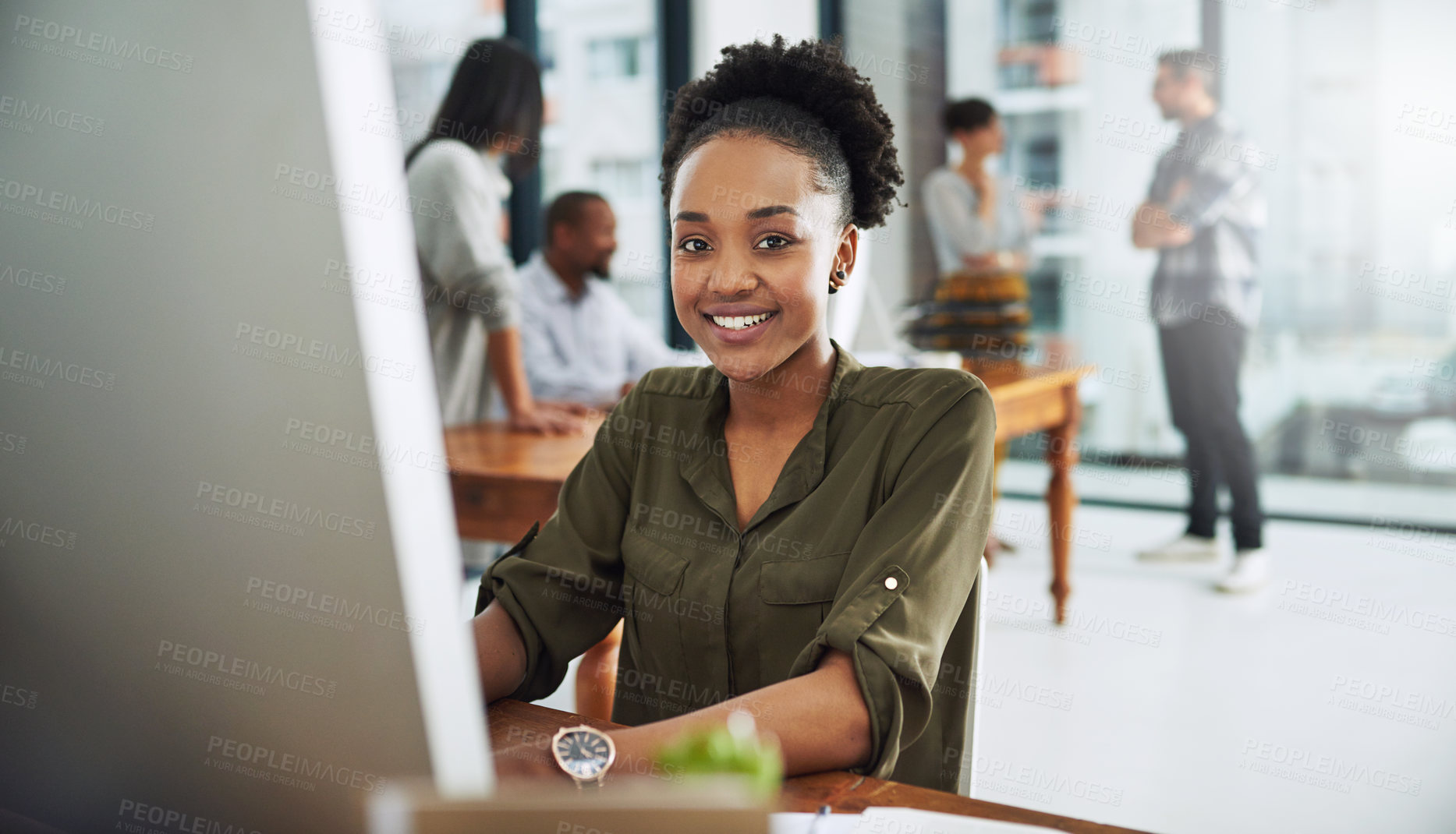 Buy stock photo Portrait of a young businesswoman working on a computer in a modern office with colleagues in the background