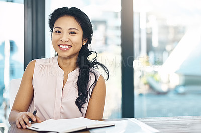 Buy stock photo Portrait of a smiling young businesswoman reading paperwork while sitting in an office