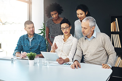 Buy stock photo Shot of a group of coworkers talking together over a digital tablet in a boardroom