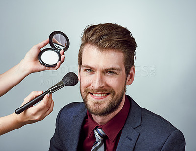 Buy stock photo Studio portrait of a handsome young man having makeup applied to his face against a gray background