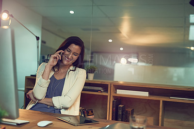 Buy stock photo Cropped shot of a young businesswoman talking on a cellphone while working late in an office
