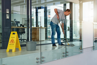 Buy stock photo Shot of a young man mopping the office floor