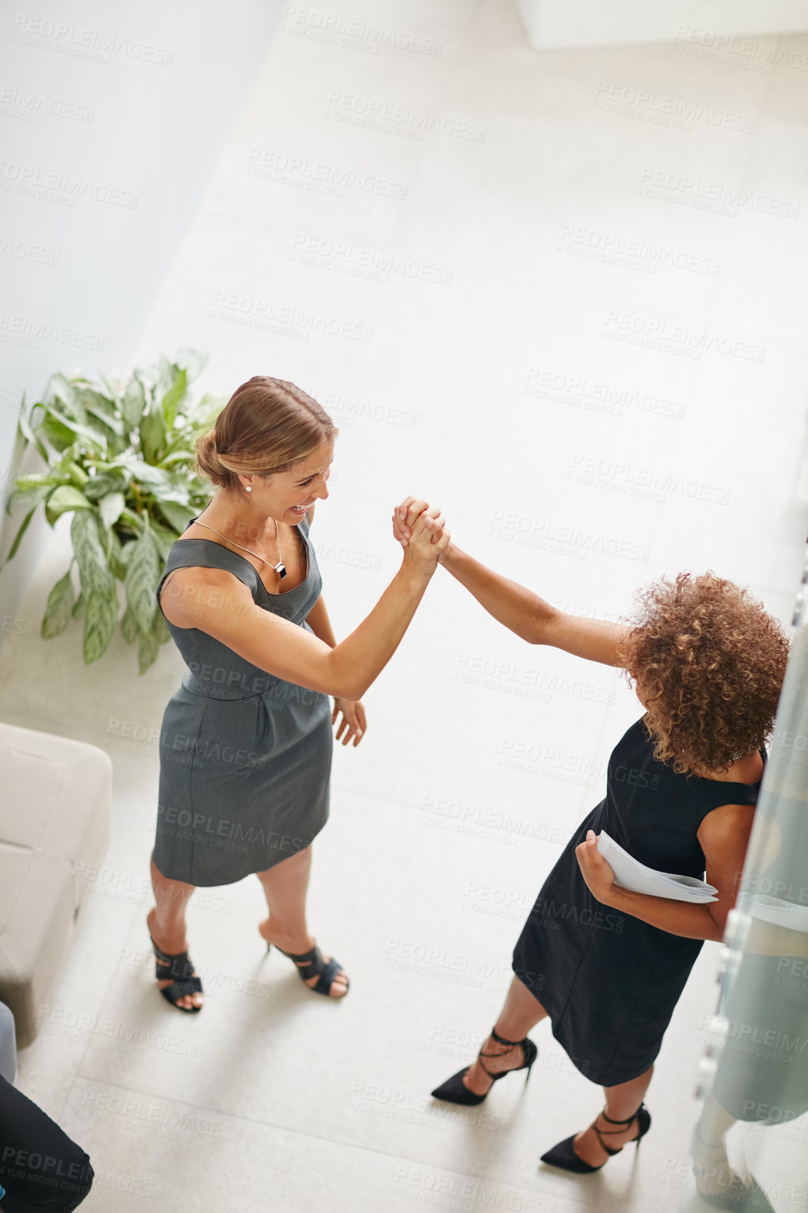 Buy stock photo High angle shot of two businesswomen high fiving together in a modern office